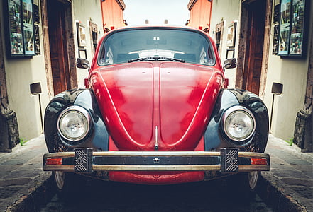 red and black Volkswagen Beetle coupe in between houses thumbnail
