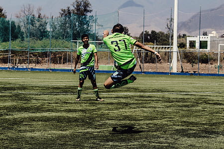 man kicking ball through man standing on green grass thumbnail