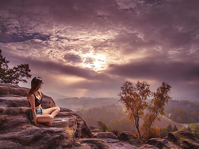 woman in black sports bra with blue denim shorts sitting on rock under cloudy day thumbnail