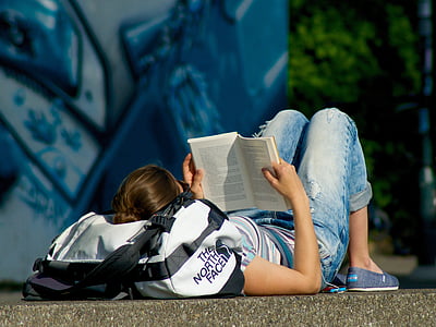 man lying on pavement reading books thumbnail