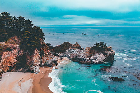 aerial photography of seashore and mountains under blue calm sky thumbnail