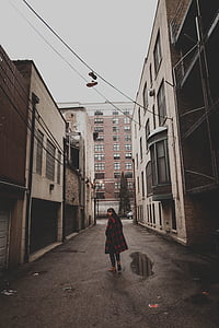 woman standing in the middle of narrow road between buildings thumbnail