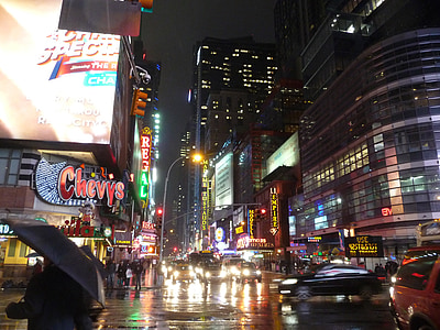 vehicles traveling on road between buildings during nighttime thumbnail