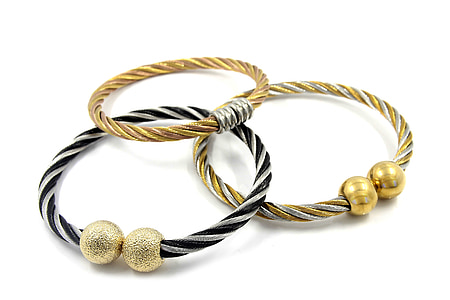 two gold-colored and one silver-colored bracelets on white surface thumbnail
