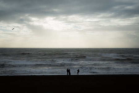silhouette of three people standing on seashore thumbnail
