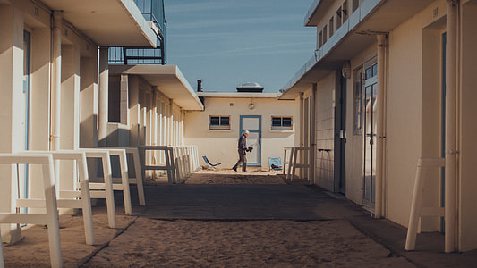 man standing between white concrete buildings under blue sky during daytime thumbnail