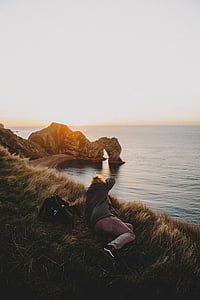 person laying in front of body of water thumbnail