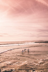 three man carrying white surfboard on seashore open sea under cloudy sky during daytime thumbnail