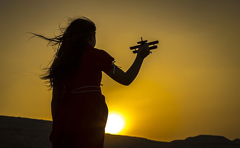 girl playing biplane toy outdoor during sunset thumbnail