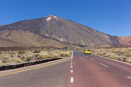 yellow vehicle on concrete road across mountain during daytime thumbnail