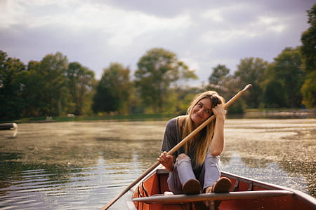 woman on brown wooden boat holding paddle thumbnail