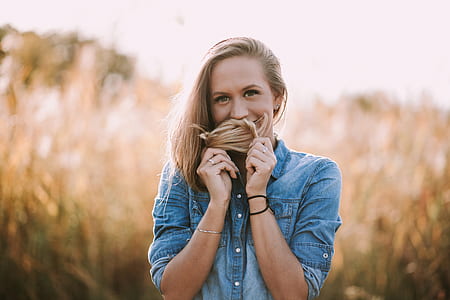 selective focus photography of woman standing while smelling her hair thumbnail