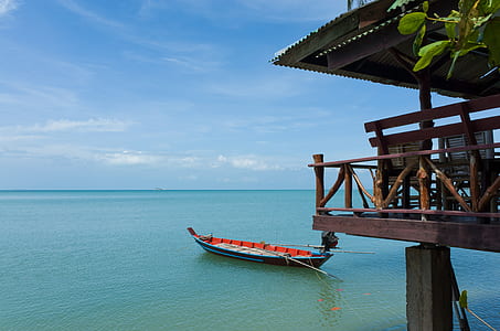 black and red sailboat near brown wooden house at daytime thumbnail