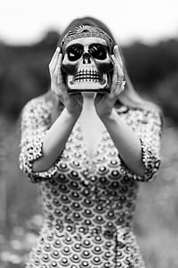 grayscale photography of woman holding skull thumbnail