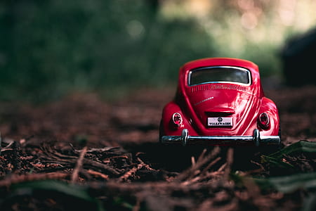 selective focus of red Volkswagen Beetle die-cast metal scale model on ground thumbnail