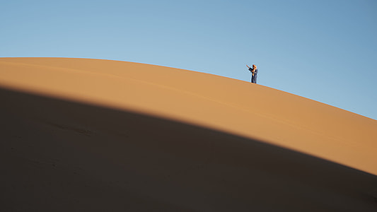 person standing on desert sand under clear sky thumbnail