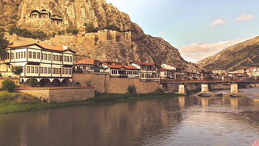 concrete houses on mountain foot near body of water thumbnail
