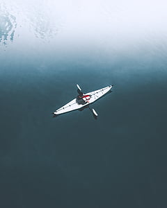 aerial photo of person riding on white kayak on body of water at daytime thumbnail