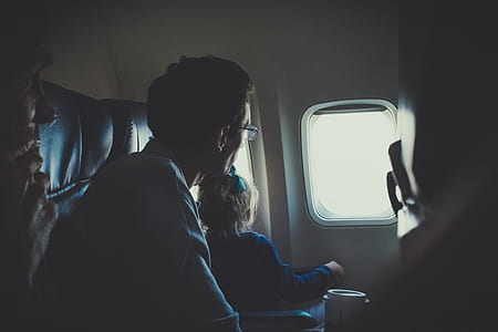 girl and man looking to passenger plane window close-up photo thumbnail