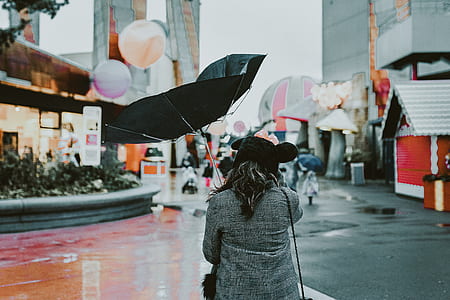 woman walking near building under brown black open umbrella thumbnail