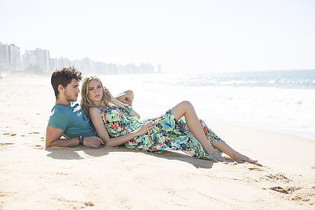 man and woman lying on sea shore thumbnail