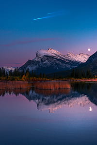shooting star over mountain and body of water thumbnail