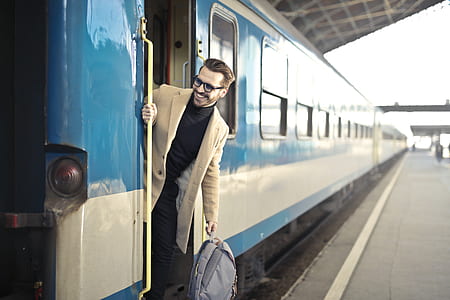 man wearing beige 2-button suit jacket holding gray backpack thumbnail