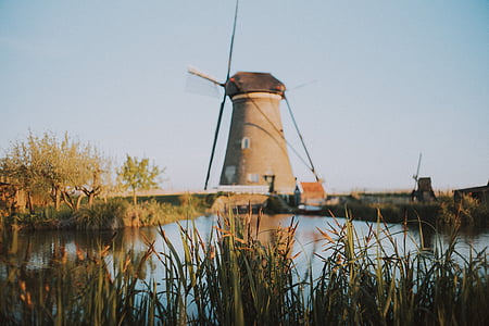 brown windmill beside body of water thumbnail