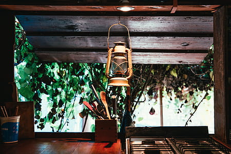 A lantern hung on a forest hut kitchen window over a cutlery holder thumbnail