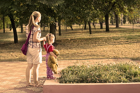 woman holding toddler girl near park during daytime thumbnail