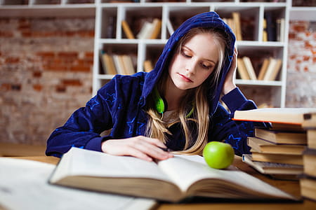 Woman Wearing Blue Jacket Sitting on Chair Near Table Reading Books thumbnail