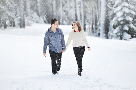 shallow focus photography of man and woman walking on snow thumbnail