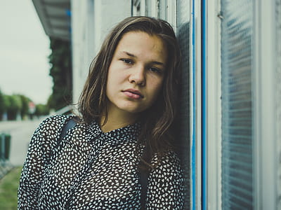 woman leaning on glass window during day thumbnail
