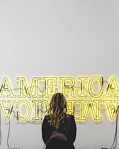 woman standing in front of yellow America signage thumbnail