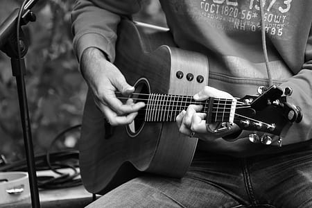 grayscale photography of person holding guitar thumbnail