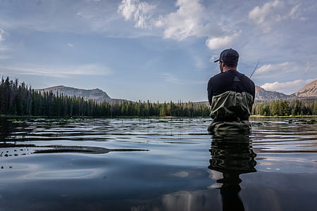 man wearing blue crew-neck t-shirt standing on the body of water thumbnail