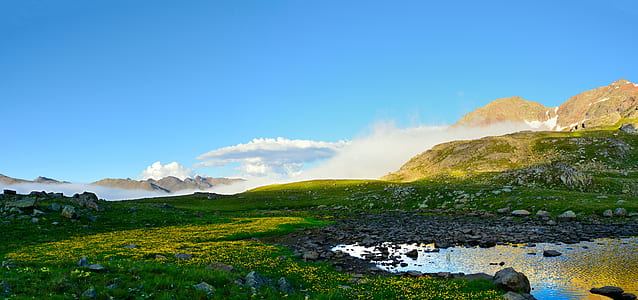 green grass mountain with body of water during daytime thumbnail