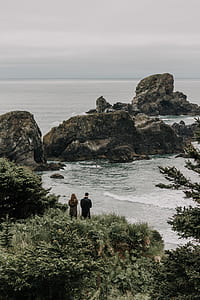 man and woman facing rock mountain on shore thumbnail