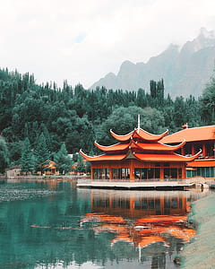 red pagoda near body of water under white clouds thumbnail