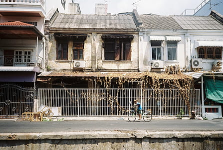 person riding bike in front of building at daytime thumbnail