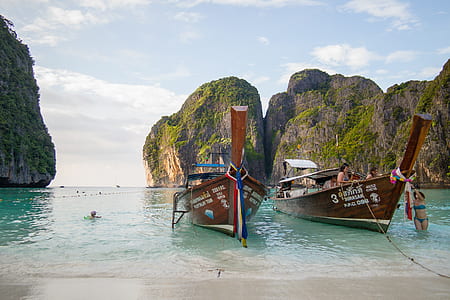 two brown boat near beach rock formation thumbnail