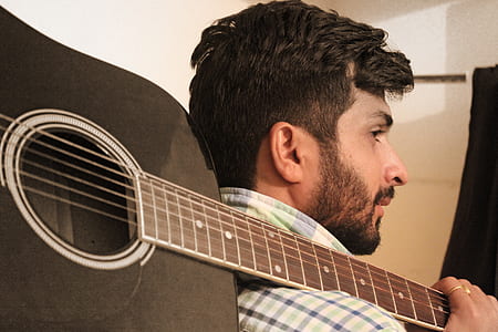 man carrying black non-cutaway acoustic guitar thumbnail