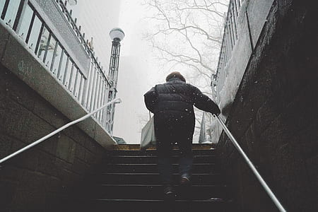 person walking up the stairs while holding on rail near post thumbnail