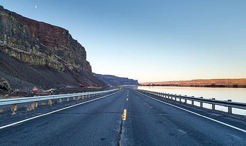 road near body of water and rock formation thumbnail