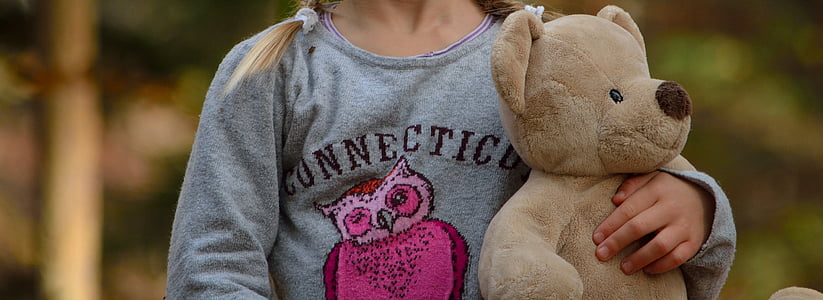 selective focus photography of girl holding bear plush toyt thumbnail