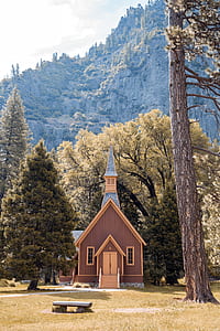 brown house beside trees near mountain under white sky thumbnail