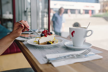 Woman Enjoying Cheese Cake and a Coffee with Fruits in a Cafeteria thumbnail