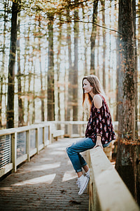 woman in purple cold-shoulder shirt sitting on beige wooden fence thumbnail