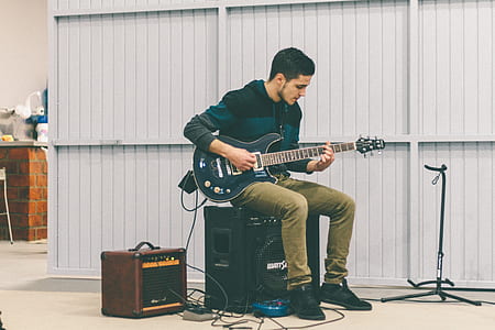 man playing guitar sitting on speaker thumbnail