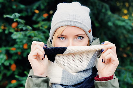 selective focus photography of woman wearing knit cap covering her mouth by scarf thumbnail